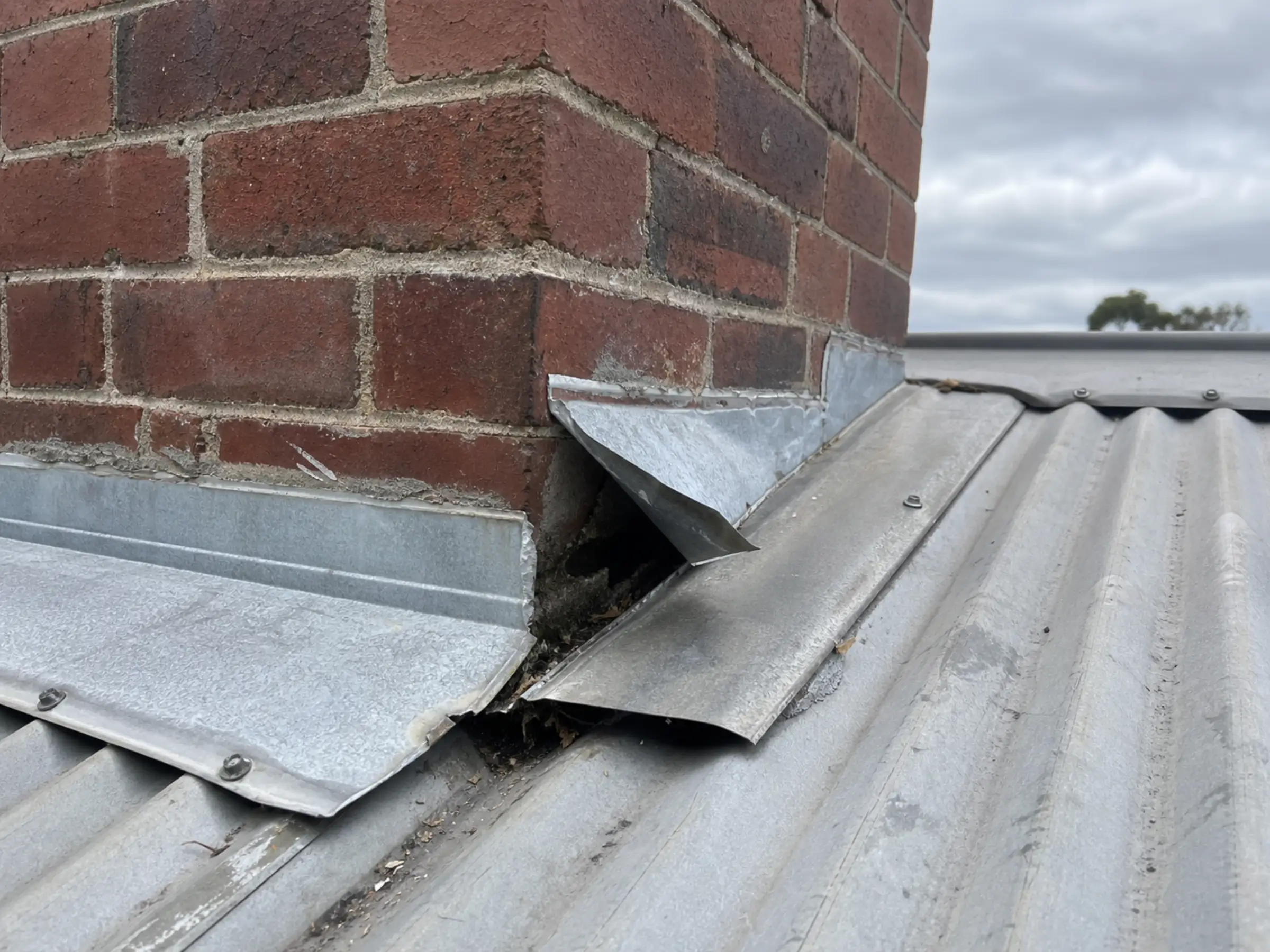 Damaged chimney flashing on a corrugated roof